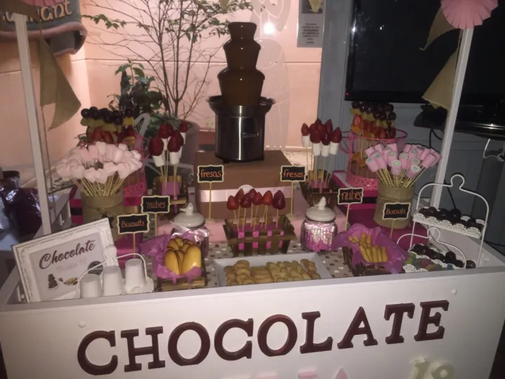 Carrito de fuente de chocolate con brochetas de fruta y nubes en un evento
