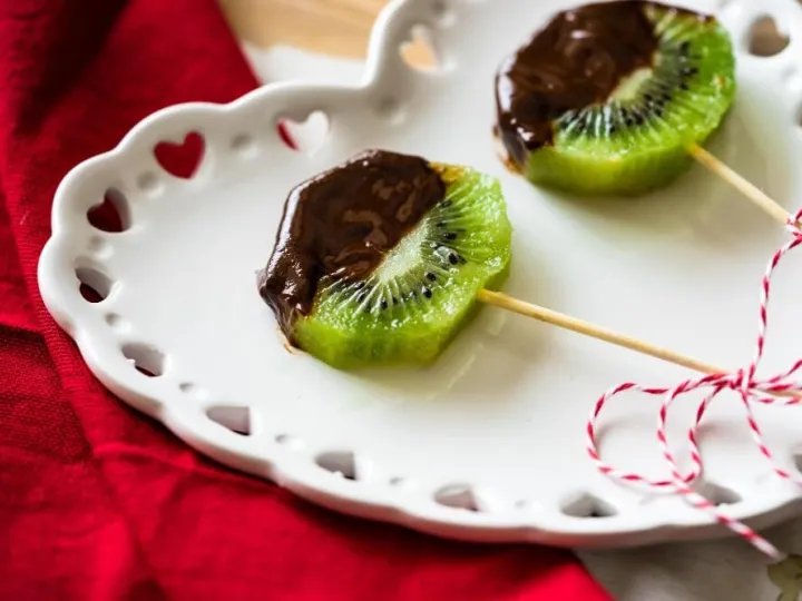 Rodajas de kiwi bañadas en chocolate en un palito