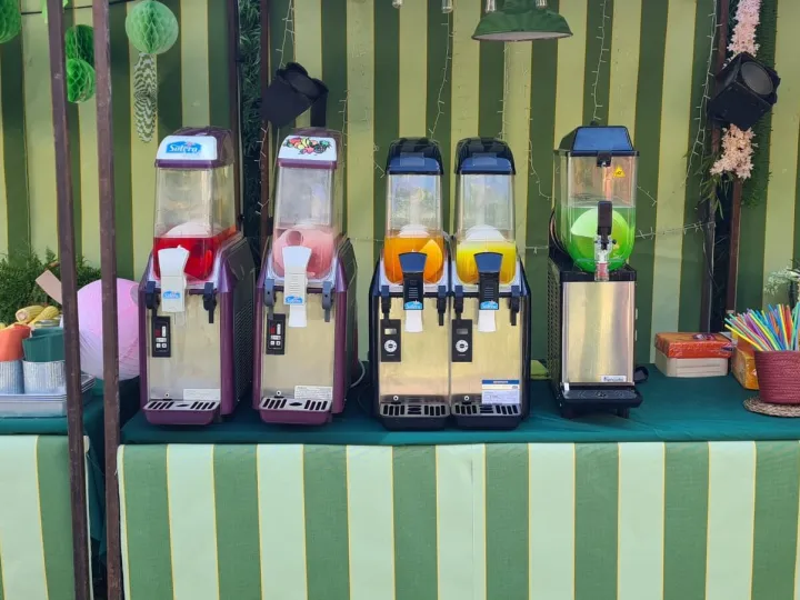 Barra de granizados con cinco máquinas de colores en un stand de rayas verdes