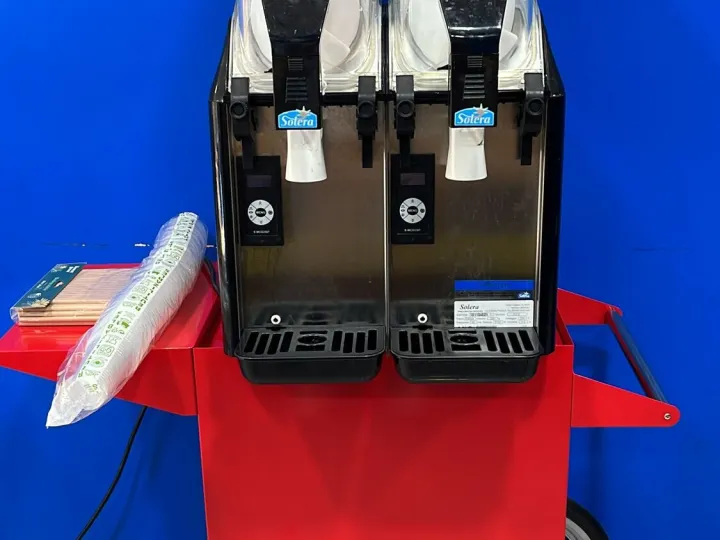 Máquina de granizados de dos cubas sobre carrito rojo con vasos y pajitas