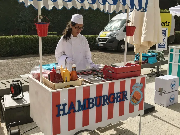 Cocinera en un carrito de hamburguesas rojo y blanco en un evento al aire libre