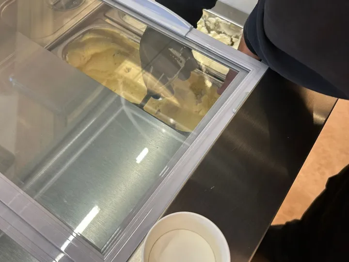 Heladero sirviendo helado artesanal desde la vitrina del carrito