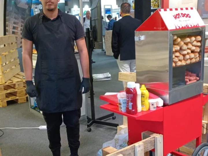 Camarero junto al carrito de hot dog en una feria