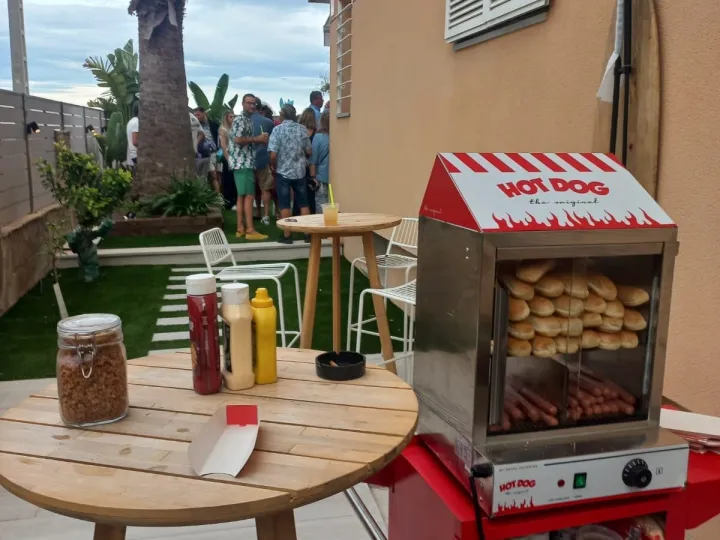 Carrito de hot dog con mesa de salsas en una terraza