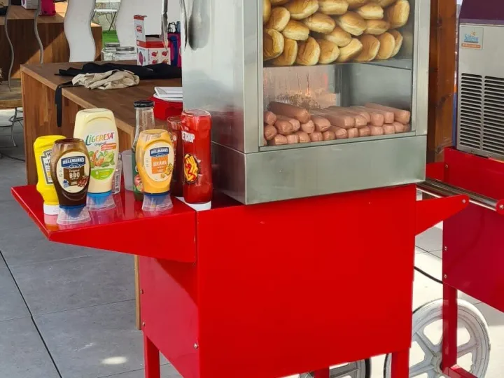 Máquina de hot dogs al vapor sobre el carrito, con pan y salchichas listos