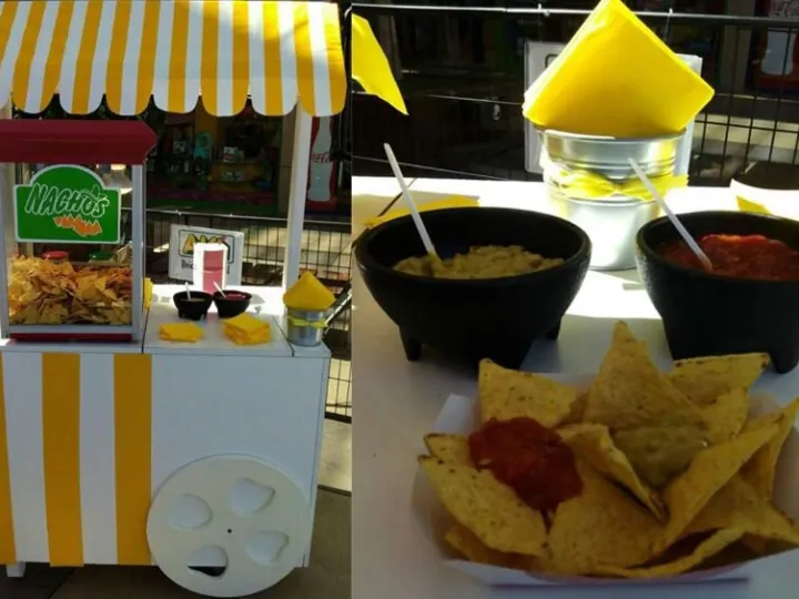Carrito de nachos con toldo amarillo junto a una bandeja de nachos con salsas
