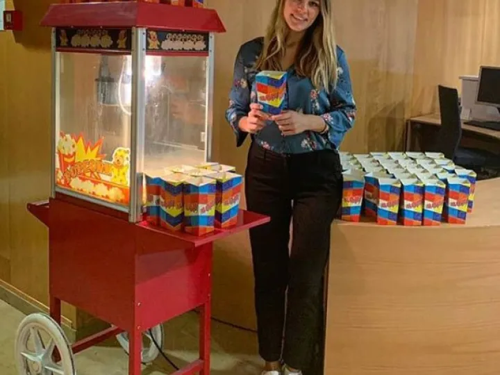 Azafata con cajas de palomitas junto al carrito en un evento de empresa