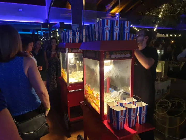 Carrito de palomitas iluminado con cajas listas para servir en una fiesta nocturna