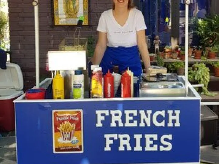 Fries cart with a blue front panel and sauces on the counter