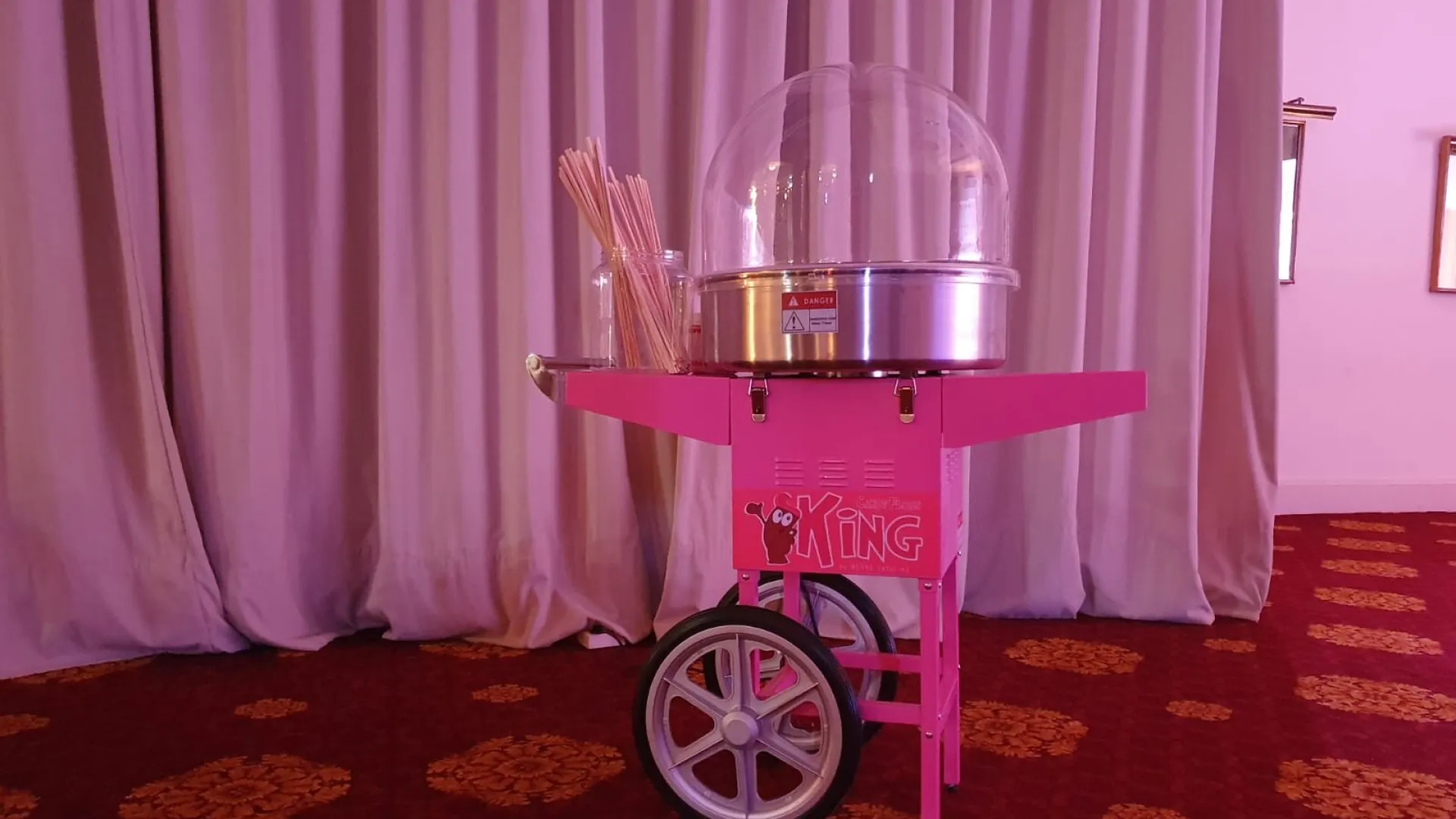 Carrito de algodón de azúcar rosa con cúpula y palos de madera, listo para el evento