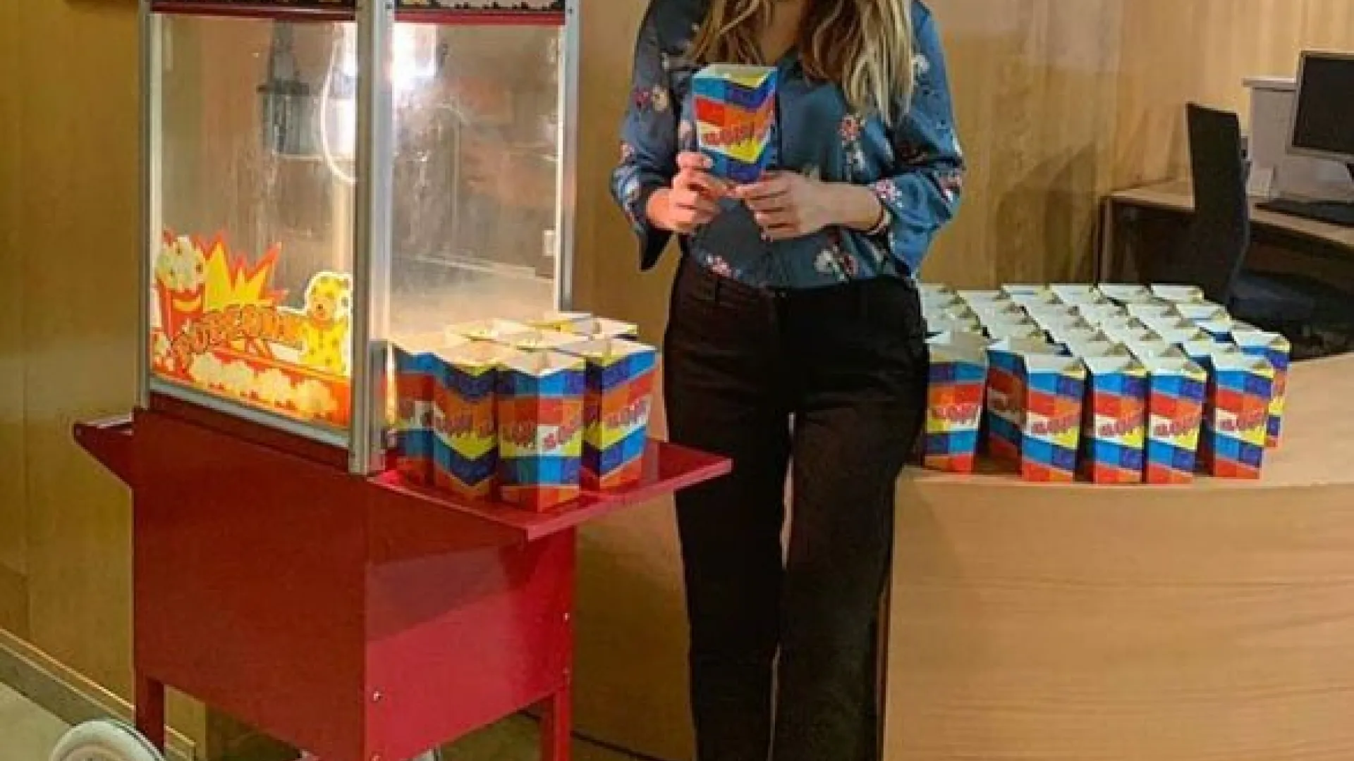 Azafata con cajas de palomitas junto al carrito en un evento de empresa