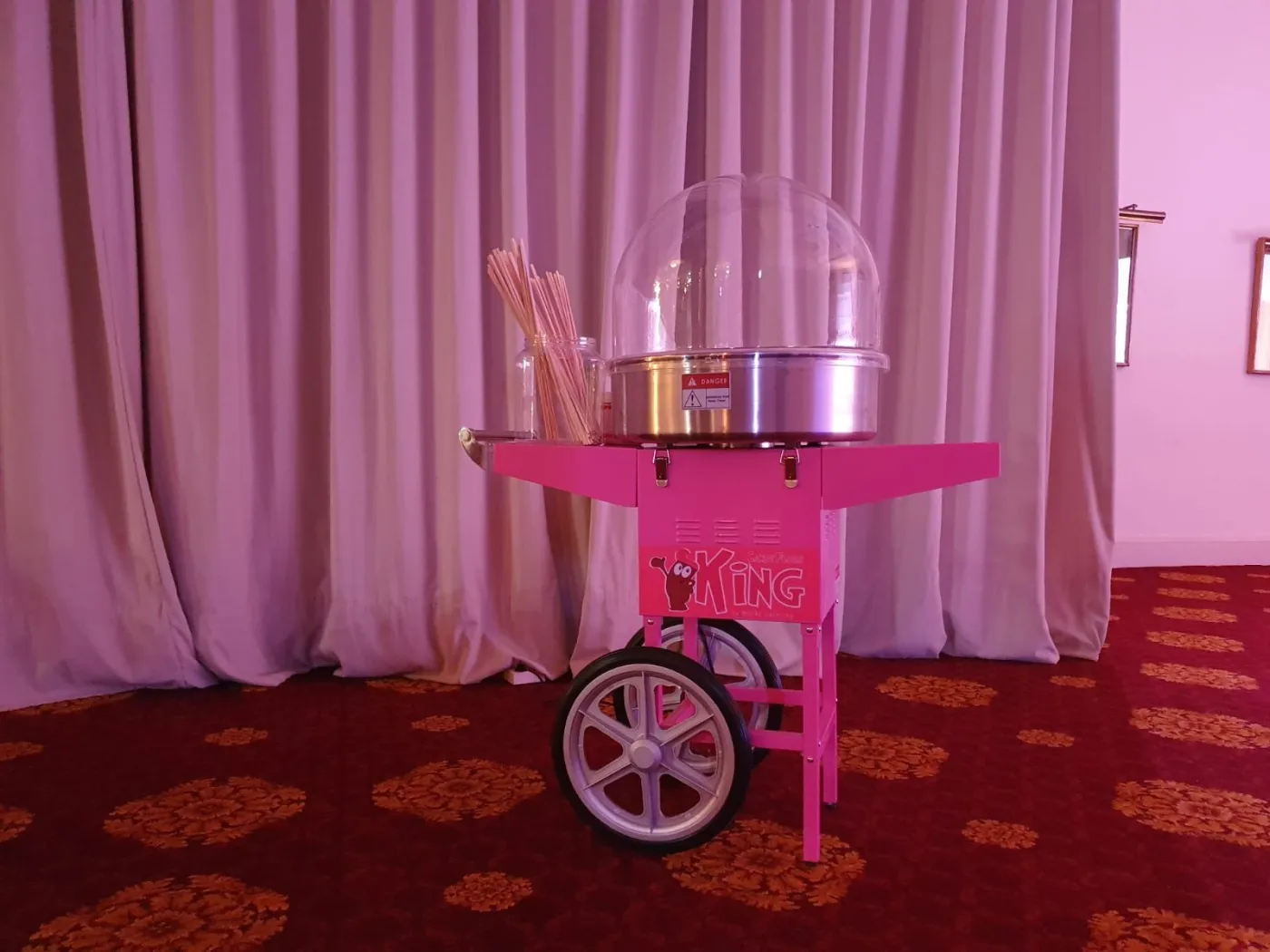 Carrito de algodón de azúcar rosa con cúpula y palos de madera, listo para el evento
