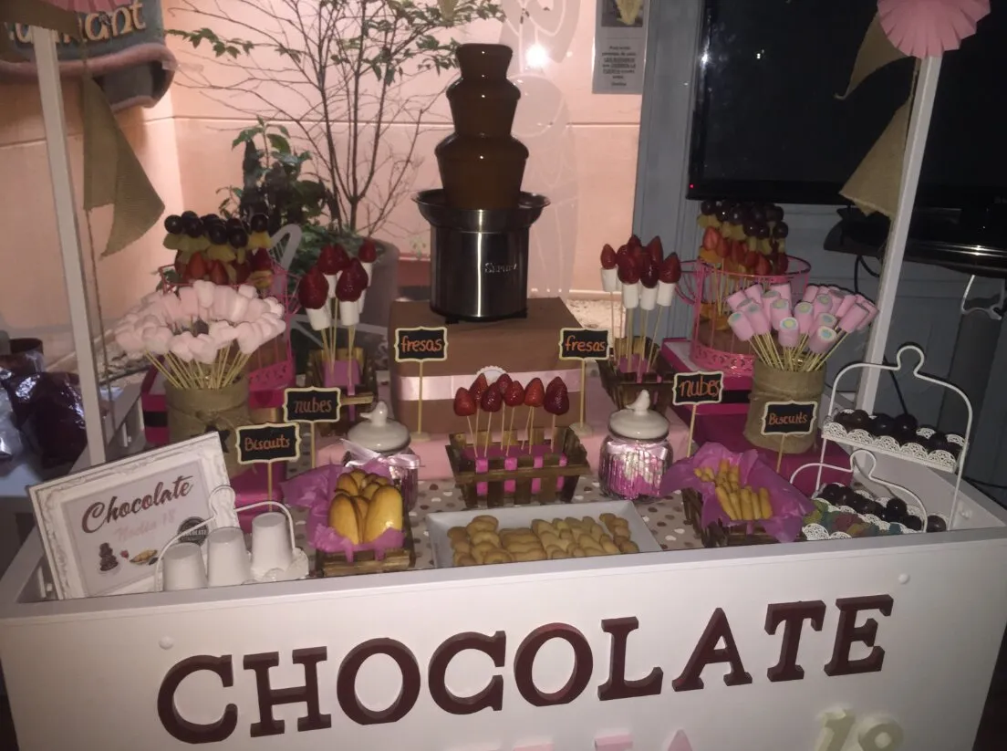 Carrito de fuente de chocolate con brochetas de fruta y nubes en un evento