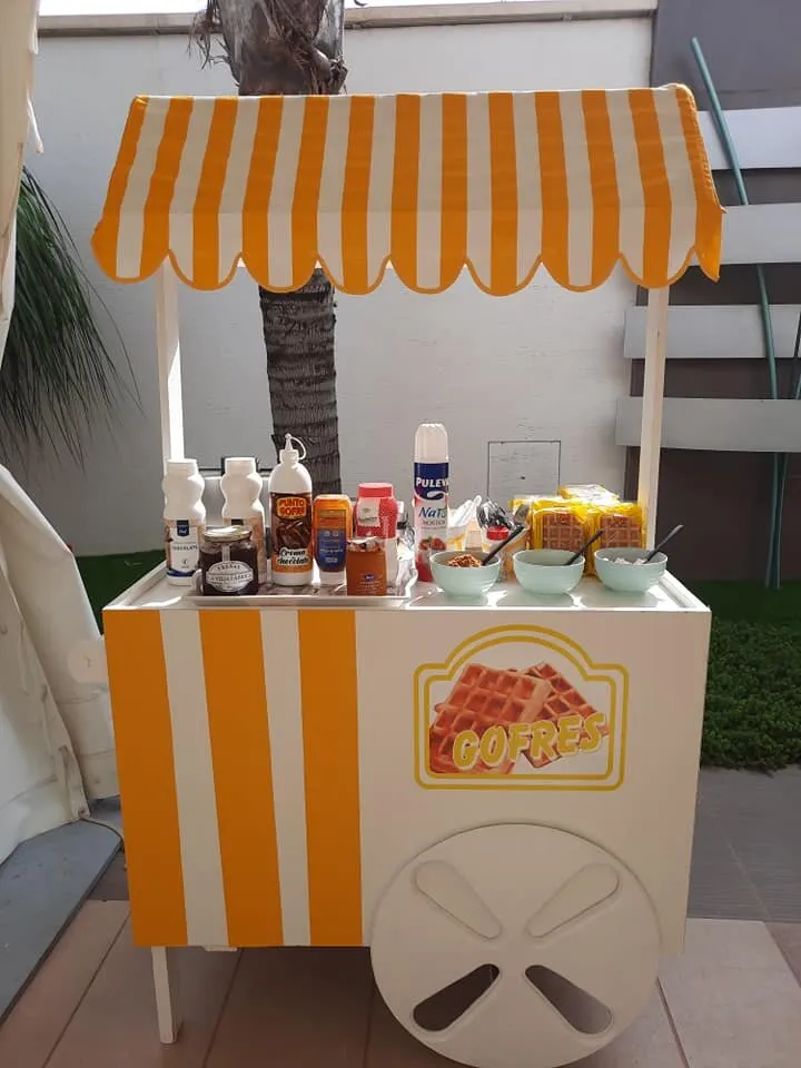 Carrito de gofres con toldo de rayas naranjas y toppings preparados