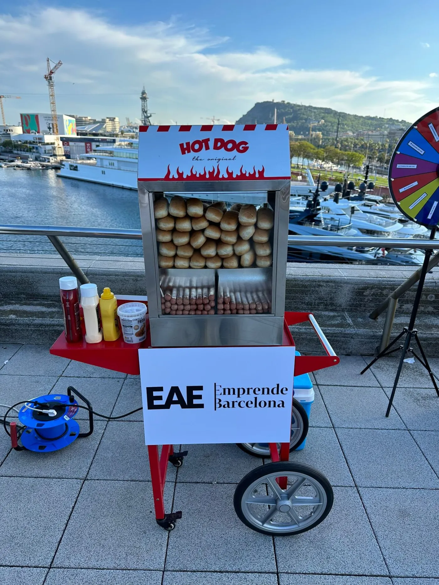 Carrito de hot dog con panel personalizado en una terraza junto al mar