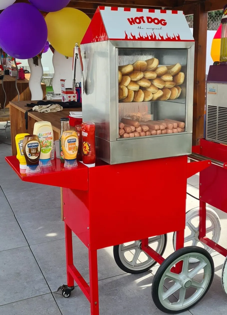 Máquina de hot dogs al vapor sobre el carrito, con pan y salchichas listos