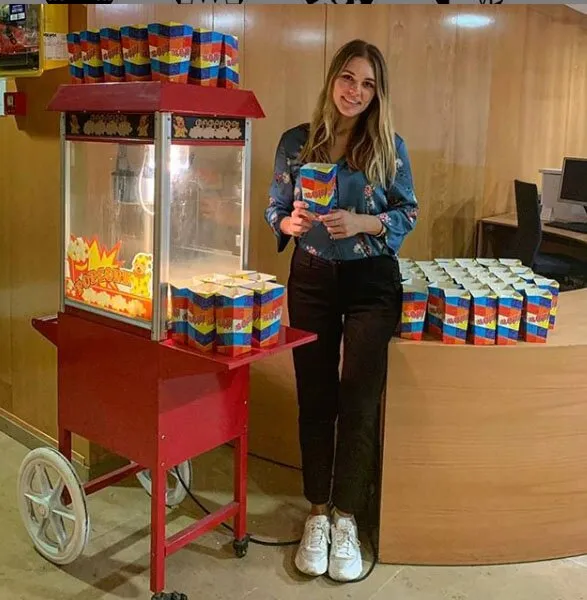 Azafata con cajas de palomitas junto al carrito en un evento de empresa