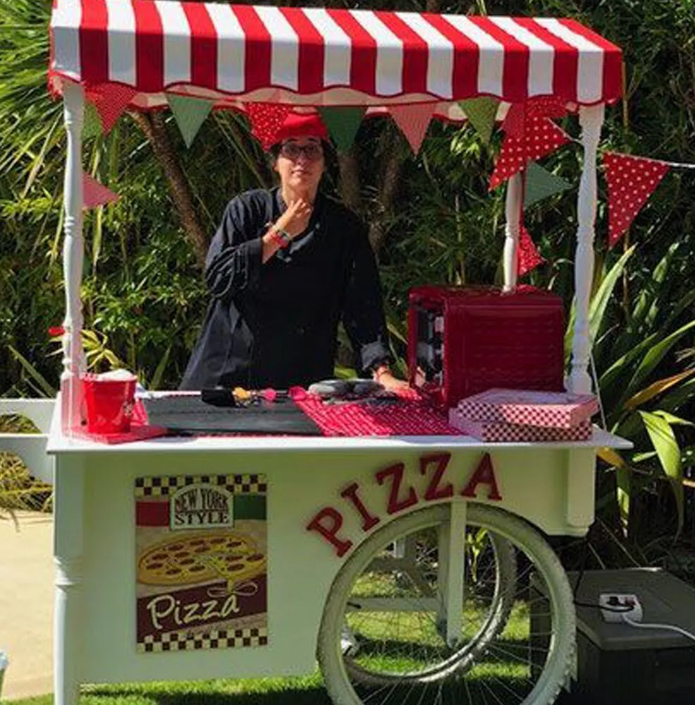 Pizza cart with a red and white striped awning in a garden